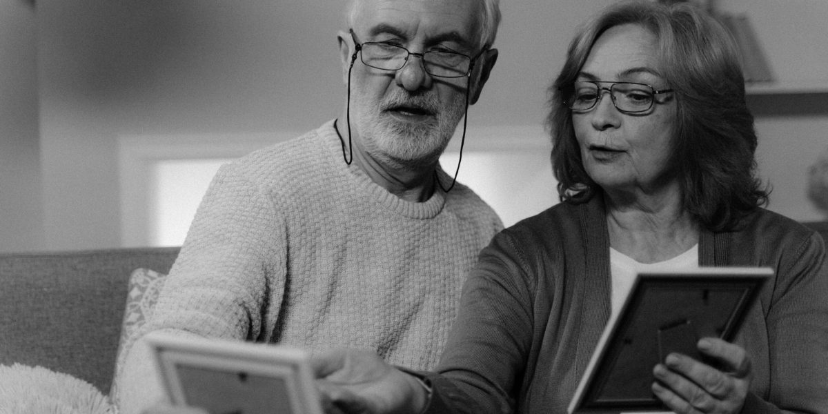 Senior couple cherishing old photographs at home, sharing memories.